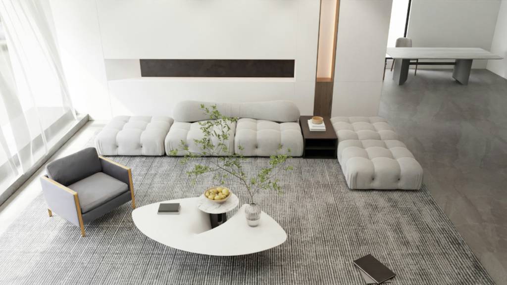Un salon moderne comprenant un grand canapé en forme de L, un fauteuil gris, une table basse ovale blanche à la décoration minimaliste et de grandes fenêtres avec des rideaux transparents.